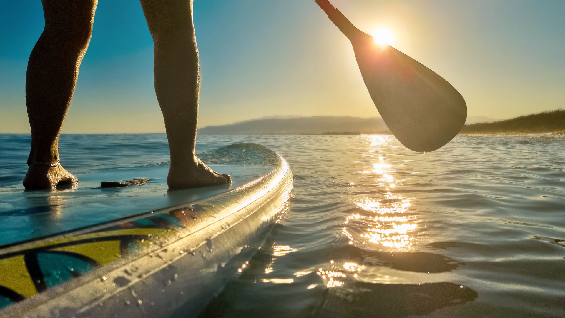 Tourist paddleboarding in Engure Marina during sunrise